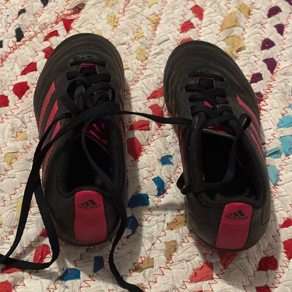 A pair of cleats brand Adidas for age 7 to 10-year-olds. With shin guards.